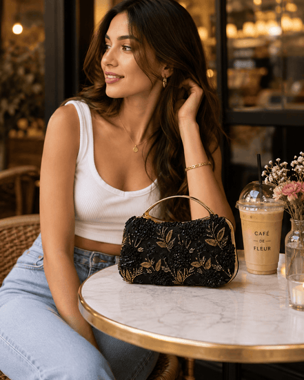 Black floral clutch bag with gold embroidered flowers, styled on table