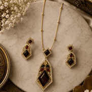 Gold-tone pendant necklace with matching drop earrings, red and blue gem stones.