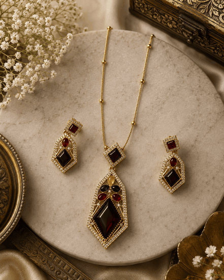 Gold-tone pendant necklace with matching drop earrings, red and blue gem stones.