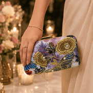 Gold-tone floral clutch with multicolor print, held by hand with clasp