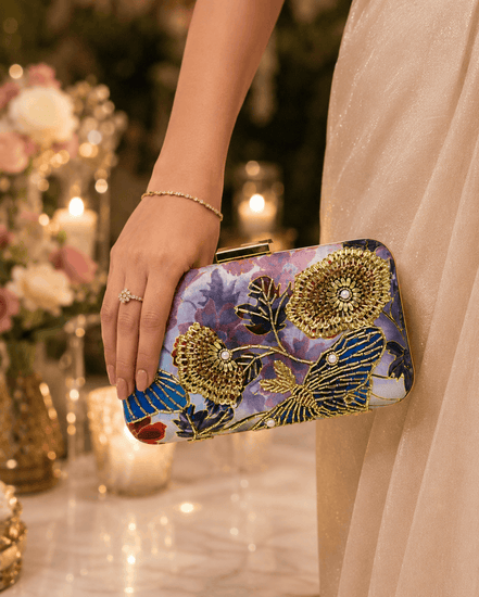 Gold-tone floral clutch with multicolor print, held by hand with clasp