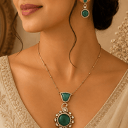 Emerald pendant necklace with teardrop center and matching drop earrings worn by model