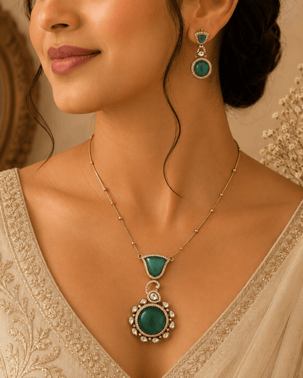 Emerald pendant necklace with teardrop center and matching drop earrings worn by model