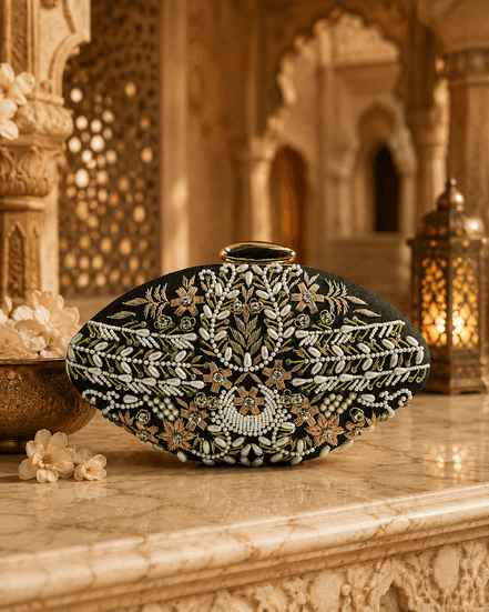 Embellished oval clutch with green beads and gold clasp on black fabric, front view