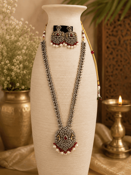 Wine necklace set bust view: layered silver-tone chains, maroon pendant, pearl jhumka earrings