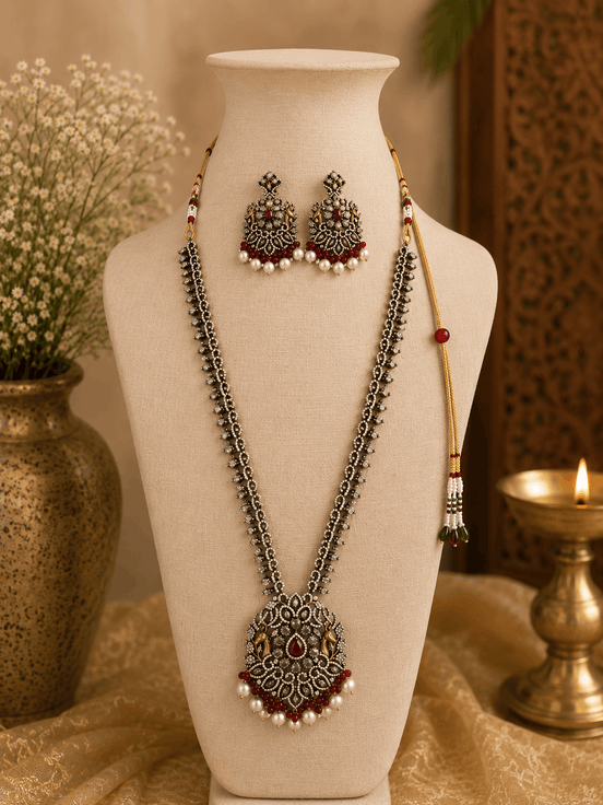 Wine necklace set on bust with layered silver-tone chains, maroon center pendant, tassel earrings