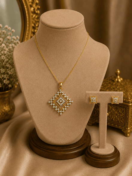 Gold-tone pendant necklace with square crystal pendant and two stud earrings on stand