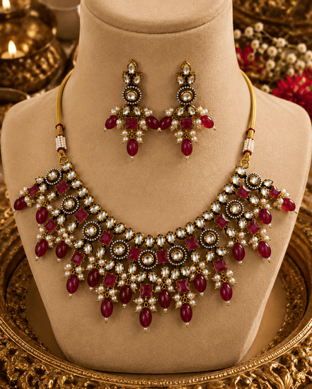 Gold-tone necklace and drop earrings with maroon-red gemstones and pearl accents