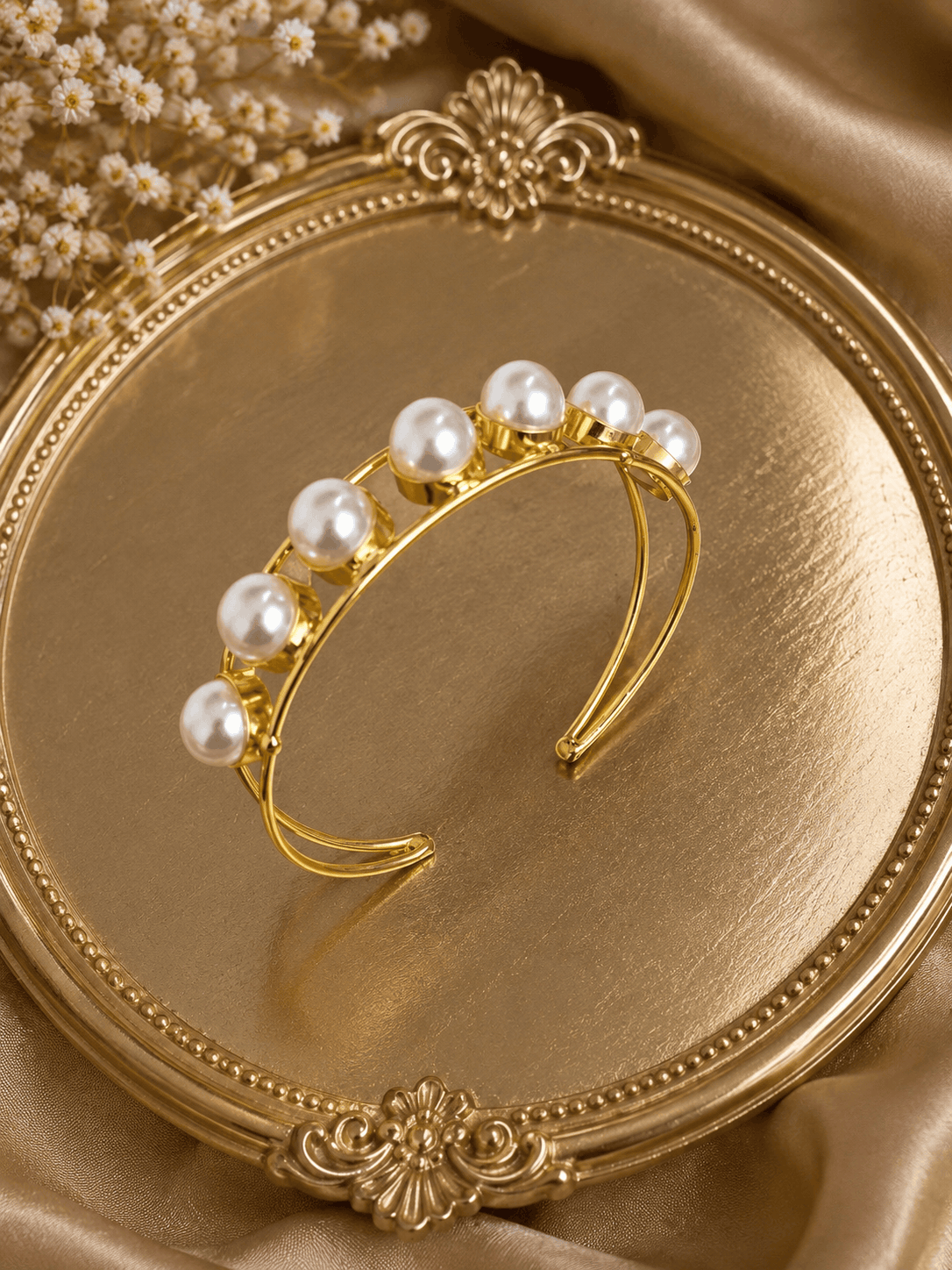 Gold-tone pearl cuff bracelet with white pearl cluster on display tray