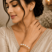 Gold-tone pearl cuff bracelet with white pearls, worn on wrist