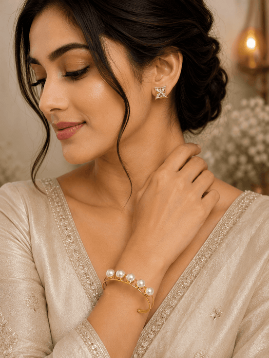 Gold-tone pearl cuff bracelet with white pearls, worn on wrist