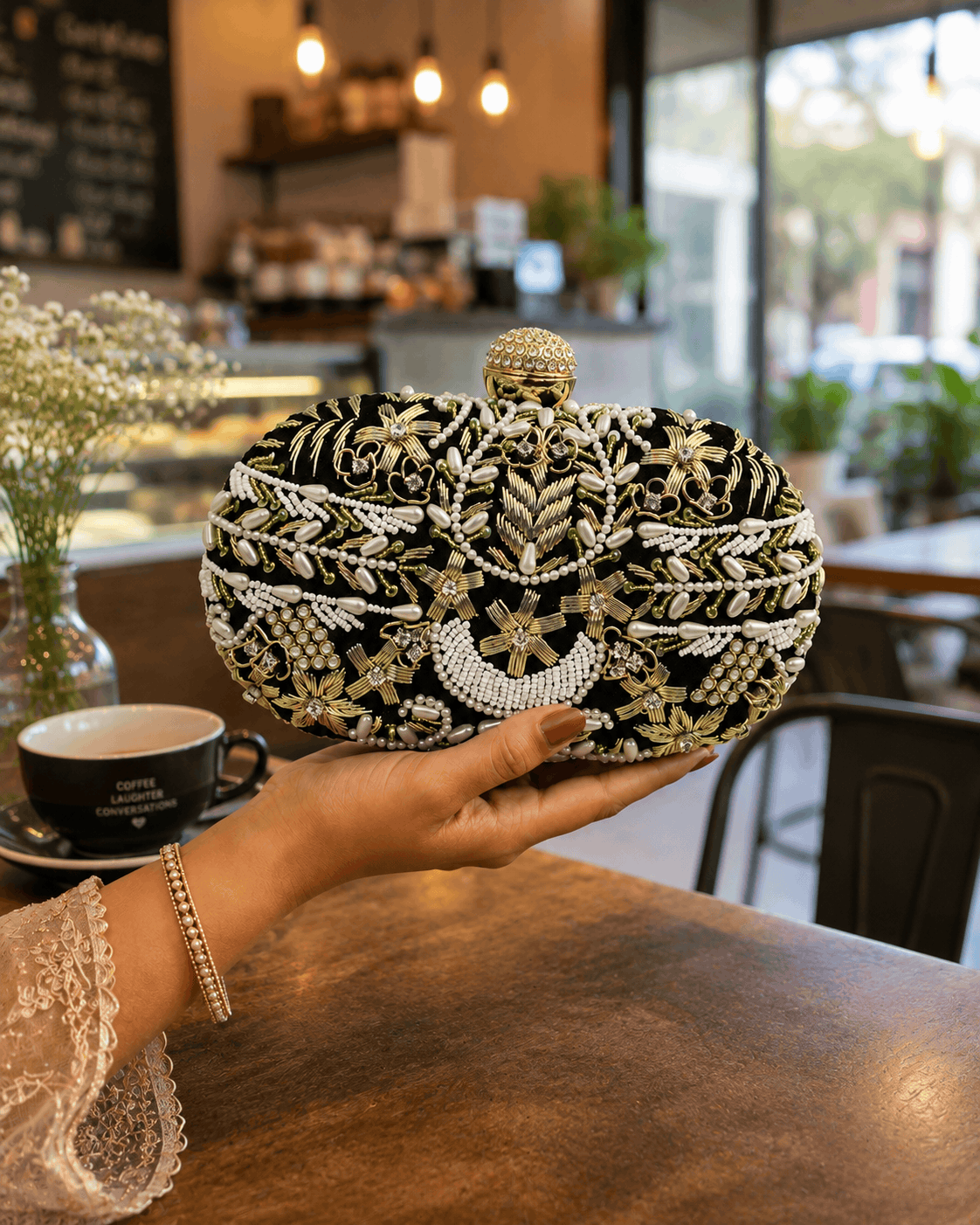 Beaded clutch with gold, black, and white embroidery; rounded top with gold clasp.