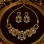 Gold-tone necklace set with purple and teal gemstones on tray; matching drop earrings