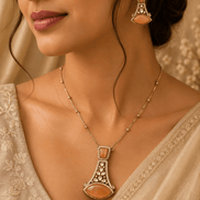 Gold-tone pendant necklace with matching dangling earrings, close-up on model