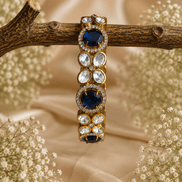 Gold-tone stone bracelet with dark blue oval stones and clear round accents, on branch