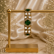 Gold-tone stone bracelet with green oval centers and clear round accents, on stand