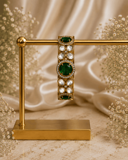 Gold-tone stone bracelet with green oval centers and clear round accents, on stand