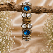 Gold-tone stone bracelet with blue oval stones and clear round accents, on branch