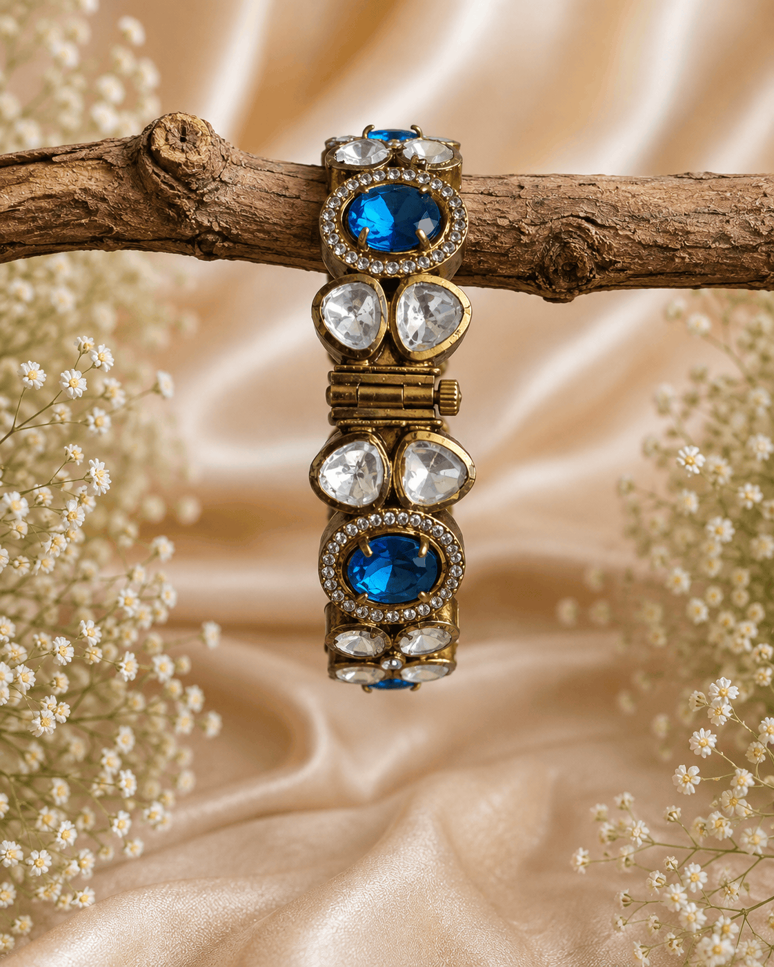 Gold-tone stone bracelet with blue oval stones and clear round accents, on branch