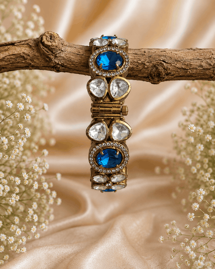 Gold-tone stone bracelet with blue oval stones and clear round accents, on branch