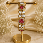 Gold-tone stone bracelet with ruby-red oval centers and clear round accents, on stand