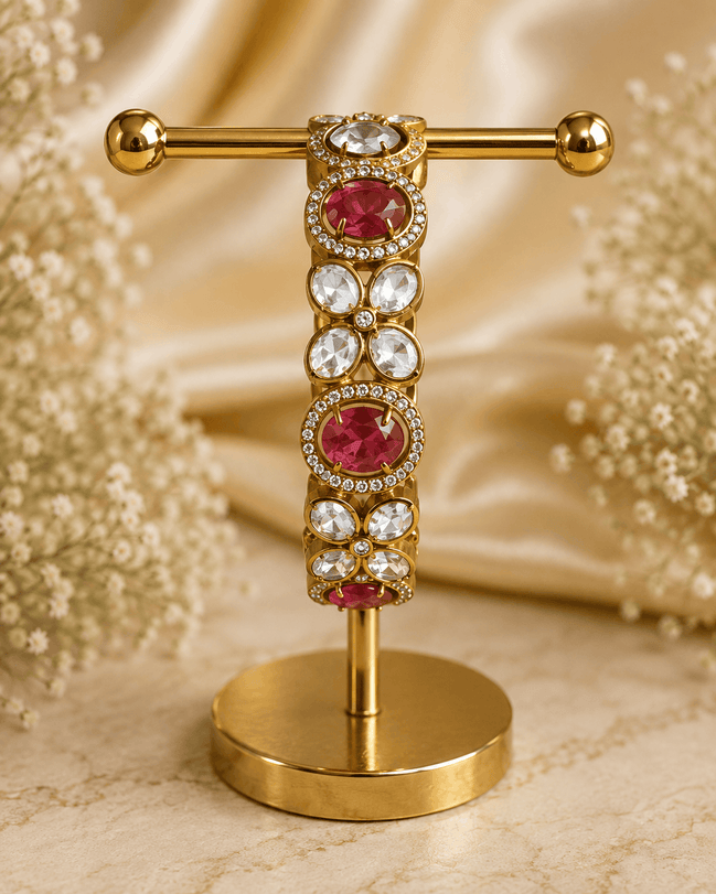 Gold-tone stone bracelet with ruby-red oval centers and clear round accents, on stand