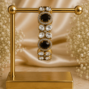Gold-tone stone bracelet with black oval centers and clear round accents, on stand