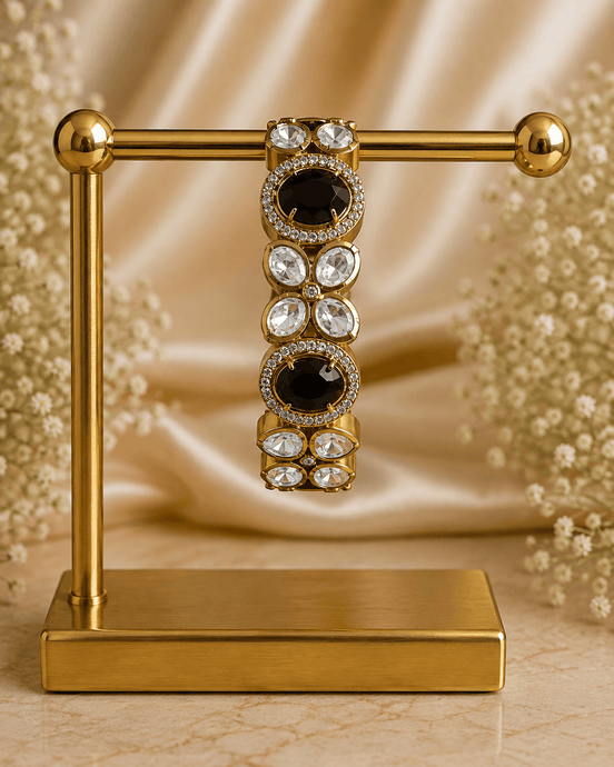 Gold-tone stone bracelet with black oval centers and clear round accents, on stand