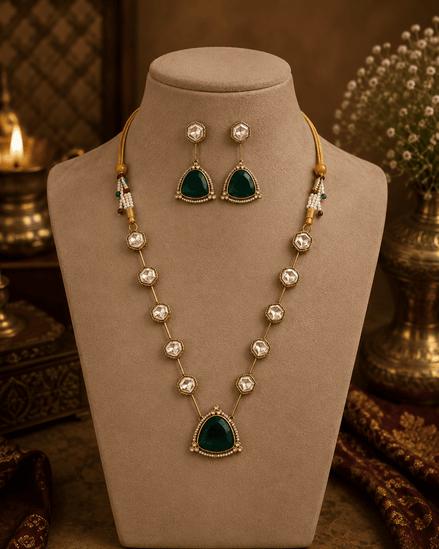 Gold-toned layered necklace with dark green teardrop pendant and multicolor bead accents