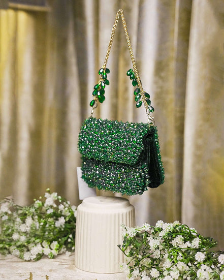 Emerald green crystal mini bag with flap front, dangling charm tassel, and shoulder chains
