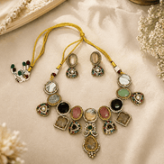 Gold-toned necklace set with green, black, pink, and white stone charms on cloth