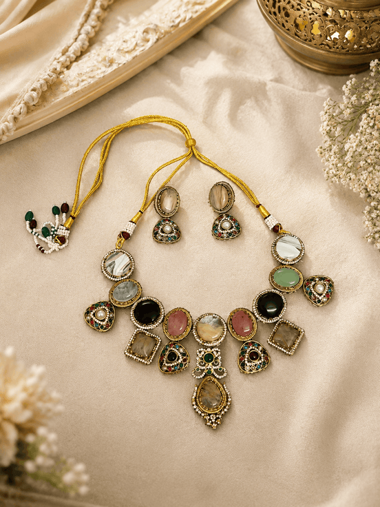 Gold-toned necklace set with green, black, pink, and white stone charms on cloth