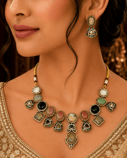 Gold-toned necklace and earrings set with green teardrop and round stone drop details