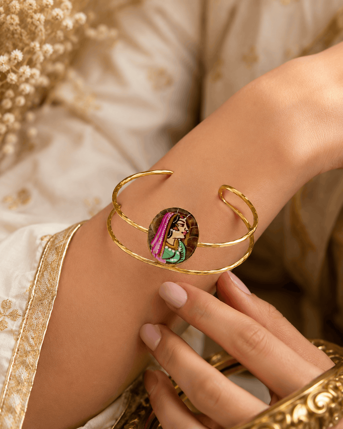 Gold-tone open cuff bracelet with oval enamel face on wrist, close-up