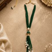 Teal green beaded tassel necklace with oval gold-tone pendant and pearl tassels