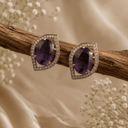 Purple teardrop halo stud earrings with pavé crystal border, gold-tone setting.