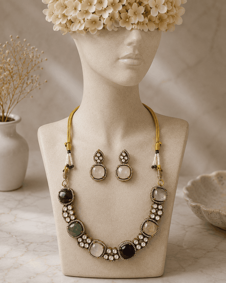 Gold-tone gemstone necklace with blue center stone, mixed round beads, and drop stud earrings