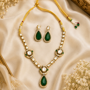 Gold-tone necklace set with green teardrop pendant, pearl beads, and matching earrings