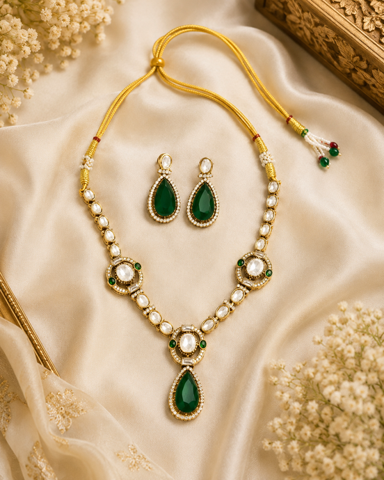 Gold-tone necklace set with green teardrop pendant, pearl beads, and matching earrings