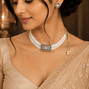 Off-white beaded choker with square centerpiece; square stud and tassel drop earrings