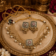 Gold-tone necklace set with central square pendant, pearl strands, and matching jhumka earrings