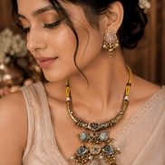 Gold choker necklace with green and red pendants and pink floral stud earrings