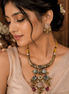 Gold choker necklace with green and red pendants and pink floral stud earrings