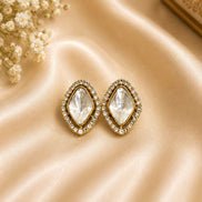 Gold-tone oval crystal stud earrings with bezel halos and clear faceted stones