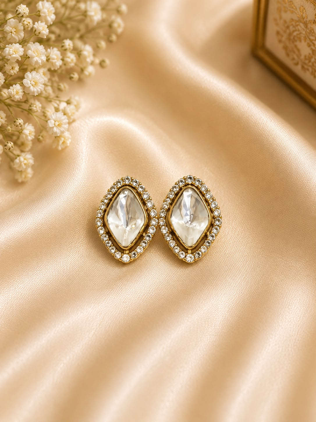 Gold-tone oval crystal stud earrings with bezel halos and clear faceted stones
