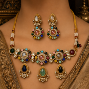 Jeweled gold-toned necklace set with matching drop earrings on neckline; multicolor stones.
