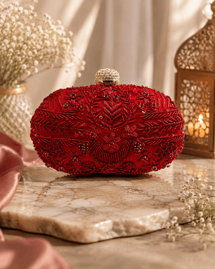 Red beaded clutch with intricate gold-toned detailing; rounded top with gold clasp.