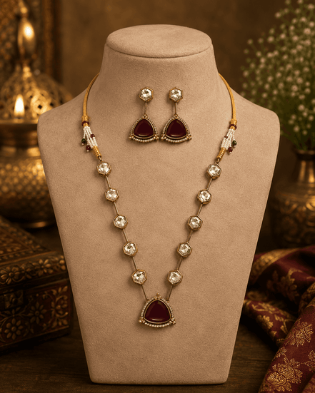 Gold-toned layered necklace with dark red teardrop pendant and long bead drop