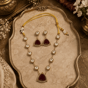 Gold-toned necklace set on tray with teardrop charms and dark red center pendant
