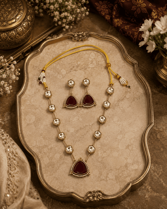 Gold-toned necklace set on tray with teardrop charms and dark red center pendant